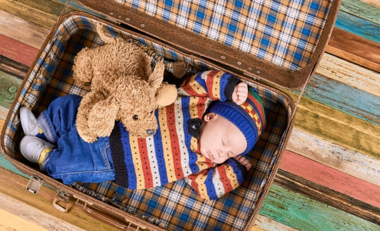 Маленький ребёнок спит в чемодане со своей игрушкой