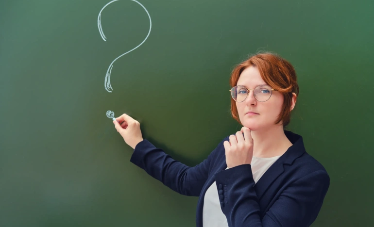 Женщина в очках нарисовала мелом знак вопроса на школьной доске